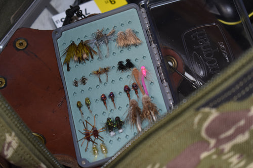 Fly fishing fly box with various flies on a green background